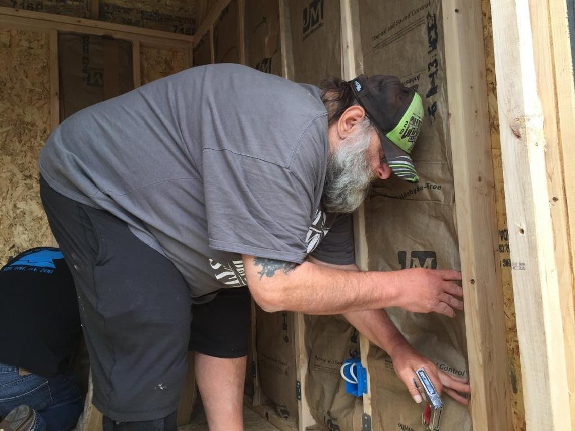 Jim Peterson with HomesNOW! staples siding into the organization's first tiny home.