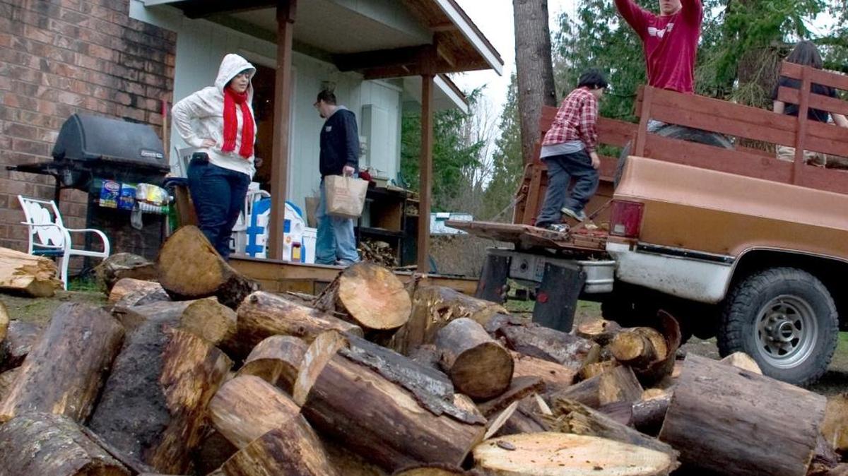 In this 2009 file photo, Kody Carlson, right, tosses firewood from his pickup as Deanna Doeden watches. People should make sure to use dry firewood to limit smoke and particle pollution.