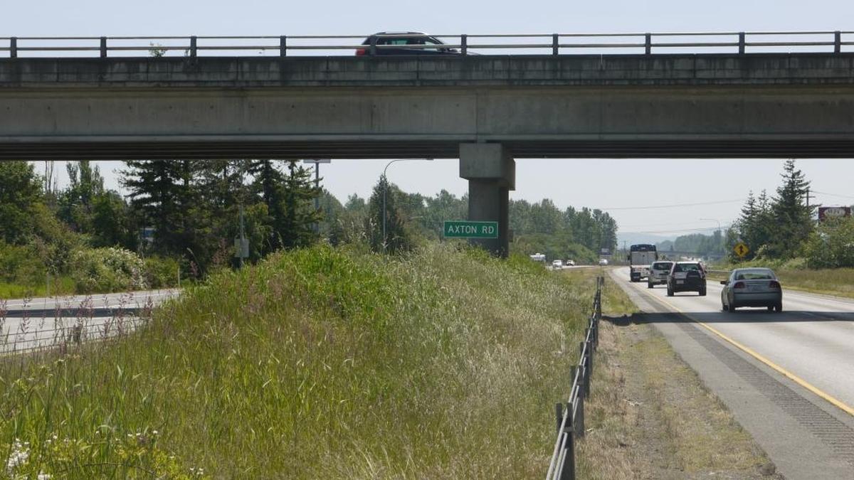The sign in the median of I-5 approaching exit 262 in Ferndale reads, “Axton Road,” but the road above is actually Main Street. There is no documentation to indicate why that road name was chosen over Main Street.