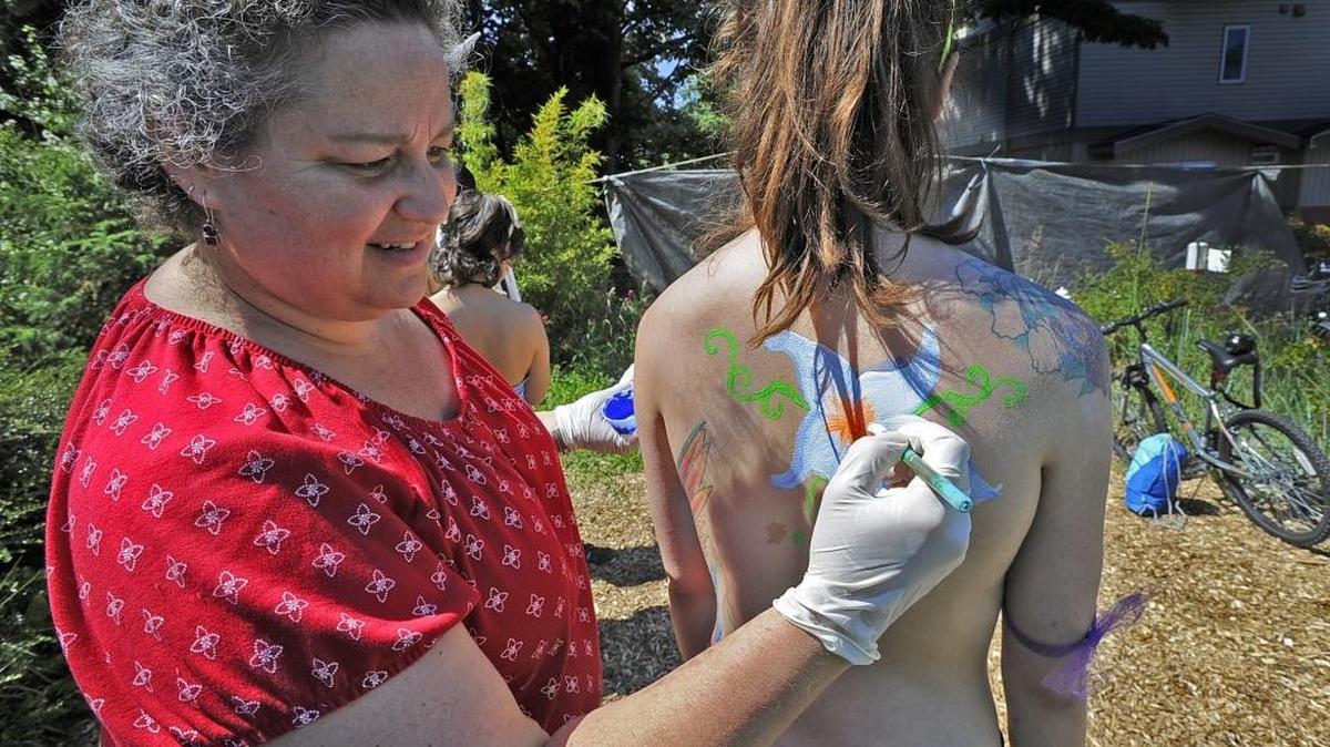 Barbara Plaskett paints Shaylene Baring on June 5, 2015, before the annual Naked Bike Ride that starts at the Hub Community Bike Shop in Bellingham. This year’s ride is Friday, June 3.
