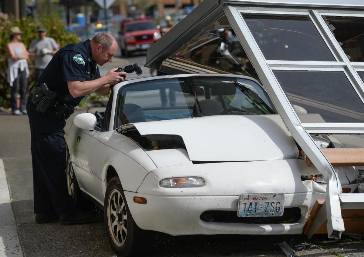 Bellingham officer Bernard Vodopich photographs the scene after a man crashed his car into a Whatcom Transportation Authority bus stop shelter on 12th Street in the Fairhaven District in Bellingham, Tuesday morning , May 9, 2017. The condition of the driver was not immediately known.