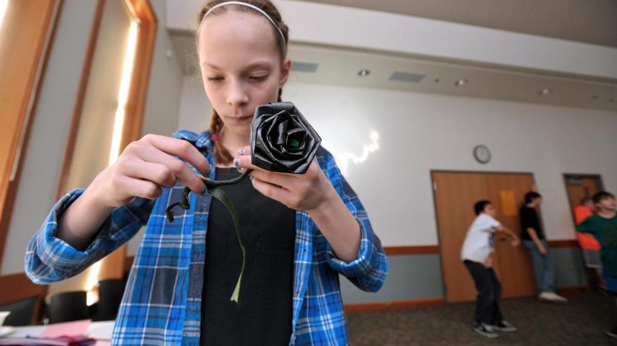Anny Olson wraps the stem of her black ribbon rose during an Anti-Valentine's Day event at the Lynden Public Library 2012.