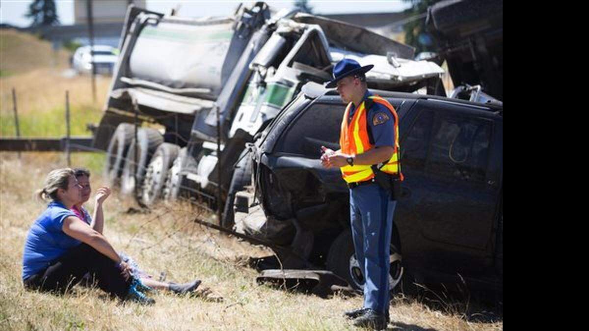 Washington State Patrol officer Mark Francis talks people who were in a large accident involving a truck carrying gravel Saturday, July 18, 2015, on Interstate 5 north of Seattle. Multiple people were injured in the crash and over a dozen vehicles were involved.