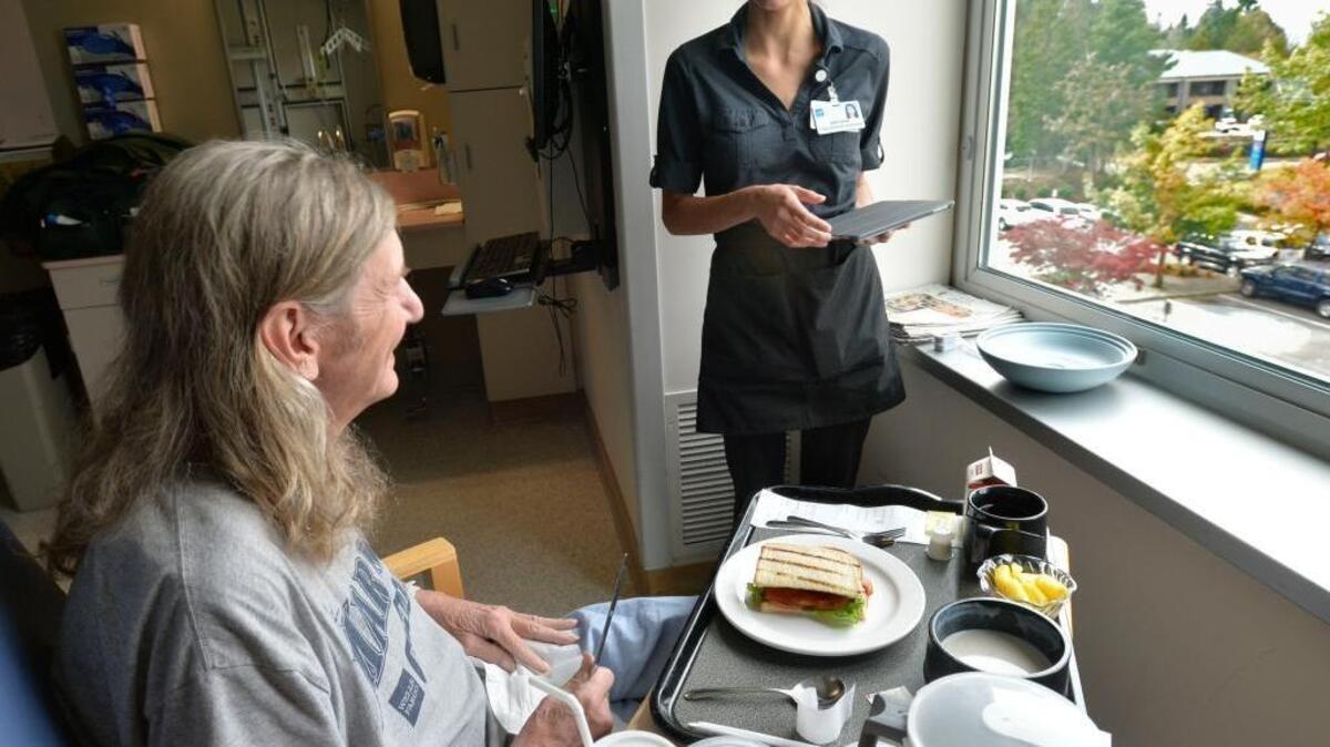 
Patient Paul Holtorf gets his lunch delivered in his room at St. Joseph hospital by food service assistant Brehana Schroyer in Bellingham, Monday, Sept. 14, 2015. In April, the hospital started a new program called Room Service that allows patients to order their meals off a menu. 
