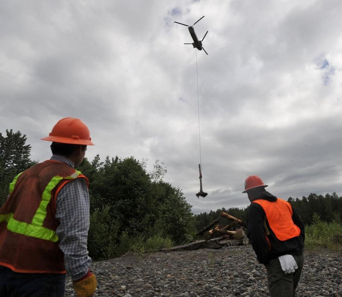 Columbia Helicopters ground crew members watch as a log is moved onto the Nooksack River to create salmon habitat. The 2010 work was a project of the Nooksack Salmon Enhancement Association.