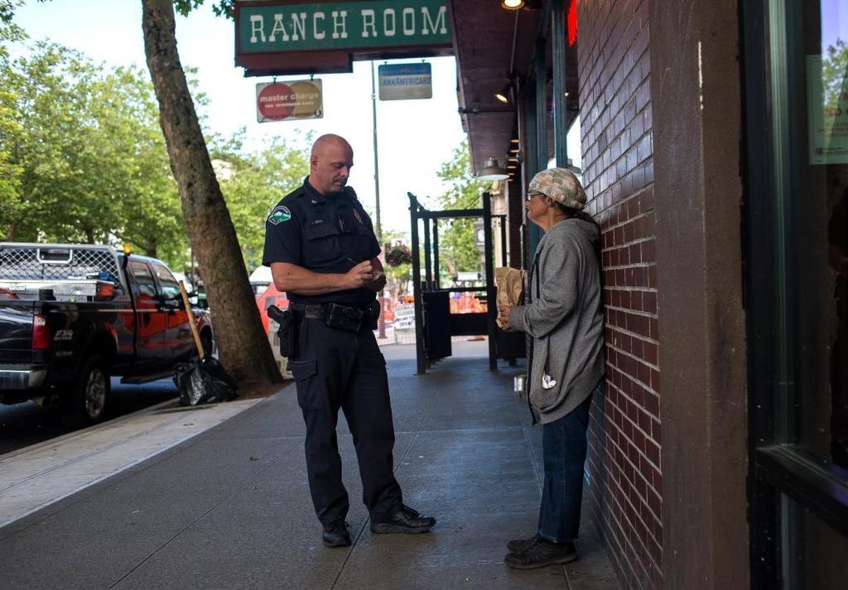 Bellingham Police Officer Jeremiah Smith, left, tells Kathleen Stouffer, 53, that she can’t drink alcohol in public on Wednesday, June 21, in Bellingham. Smith stopped to talk to Stouffer on East Holly Street during his walking patrol of downtown. He also asked Stouffer, who was homeless, if she was getting services to help her.