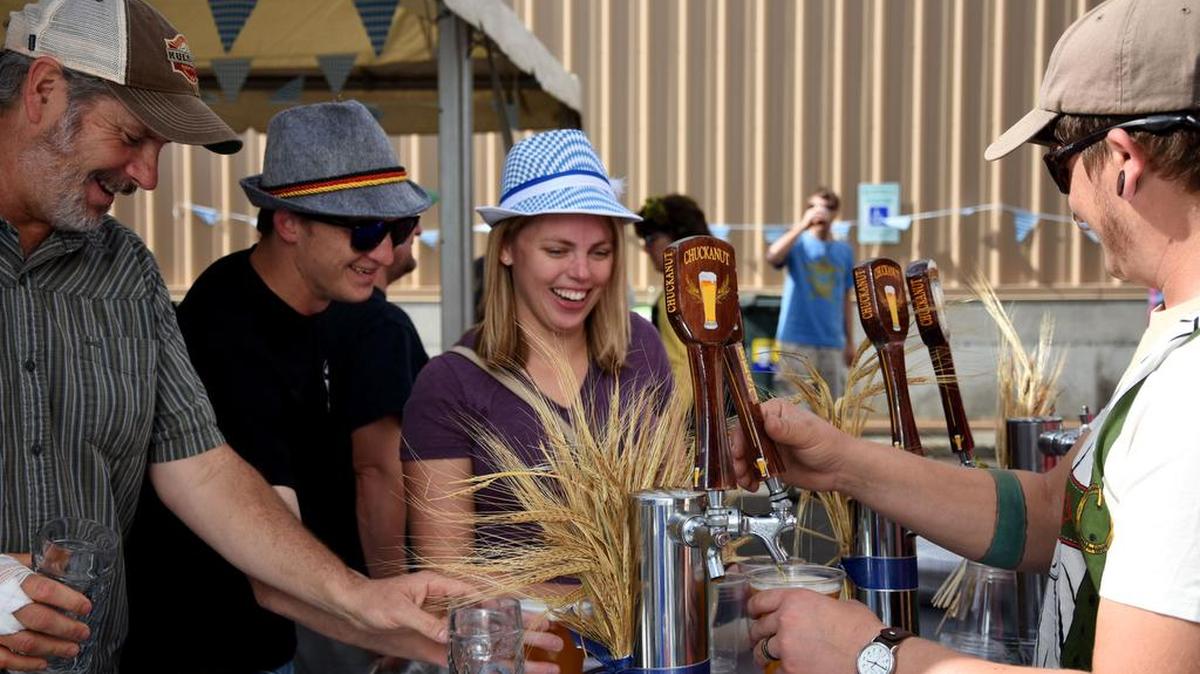 Bill Rink, Adam Hagen and Paige Hagen wait as their drinks are refilled at the outdoor tap set up at the Oktoberfest celebration at Chuckanut Brewery as part of Bellingham Beer Week on Saturday, Sept. 10, 2016.