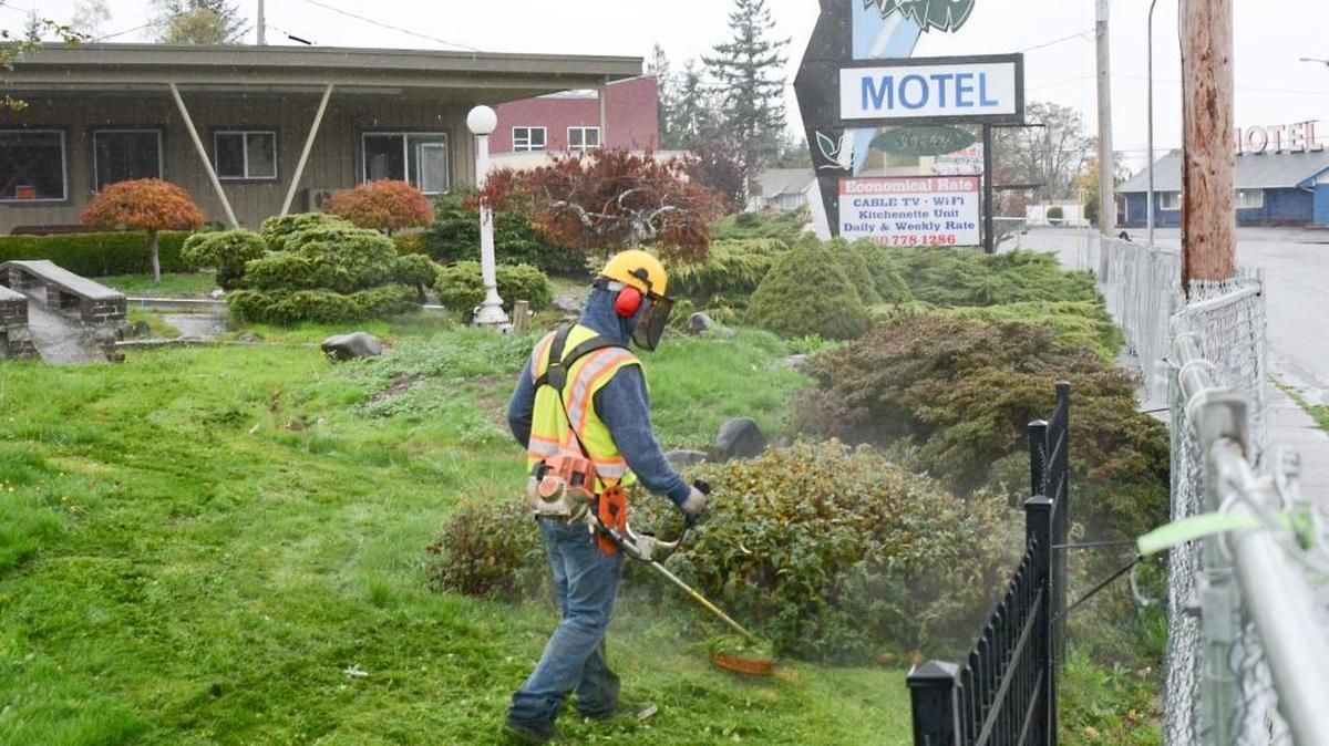 A Whatcom County Sheriff’s Office work crew member trims the lawn at the closed Aloha Motel on North Samish Way in Bellingham Wednesday, Oct. 28, 2015. Demolition of the motel is scheduled to begin in November.