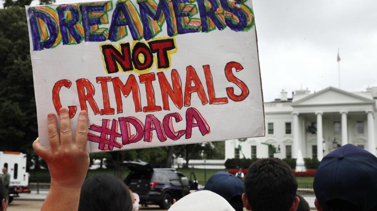 FILE- In this Aug. 15, 2017, file photo, a woman holds up a signs in support of the Deferred Action for Childhood Arrivals, or DACA, during an immigration reform rally at the White House in Washington, D.C. After months of delays, President Donald Trump is expected to decide soon on the fate of so called ”Dreamers” who were brought into the country illegally as children as he faces a looming court deadline and is digging in on appeals to his base.