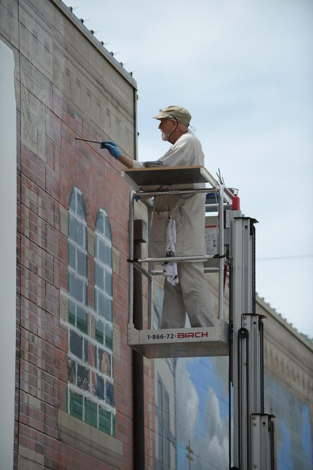 Artist Lanny Little working on restoring the Village Green mural in Fairhaven in Aug. 2013.