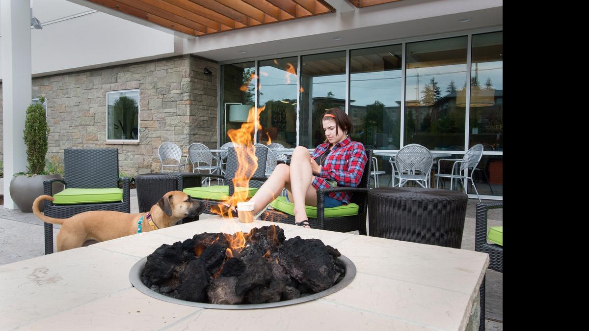 
Seattle resident Angela Pegram and her dog, Murphy, sit by a fire outside Home2 Suites by Hilton on Friday, July 10, in Bellingham, Wash.
