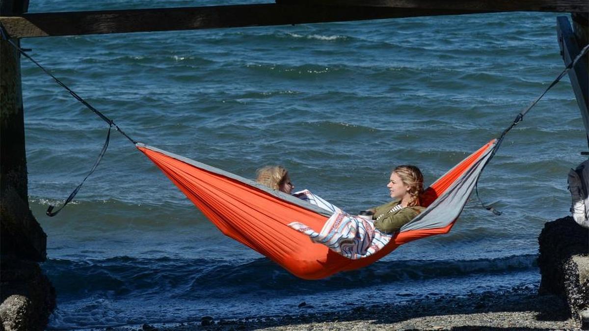 Western Washington University students Emma Raivio, left, and Jess Kirsch relax in a hammock underneath the boardwalk at Boulevard Park in Bellingham Tuesday, March 29, 2016. Kirsch calls the hammock their “portable couch.”