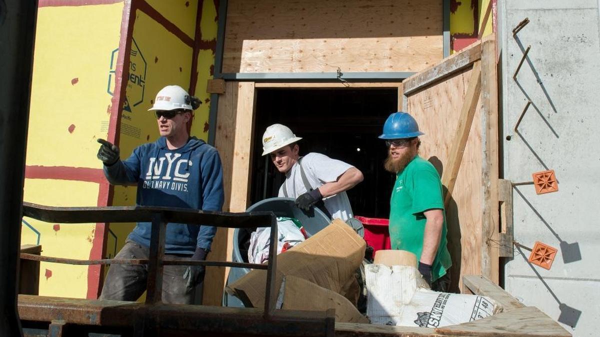 Tiger Construction employees, from left to right, Mike Hunholz, Kyle Brady and Malikai Knight, remove trash and debris from the construction site of Options High School on Friday, Feb. 17, in Bellingham.