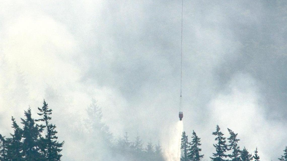 A helicopter drops water on the Stewart Mountain fire east of Bellingham, Monday, July 6, 2015.