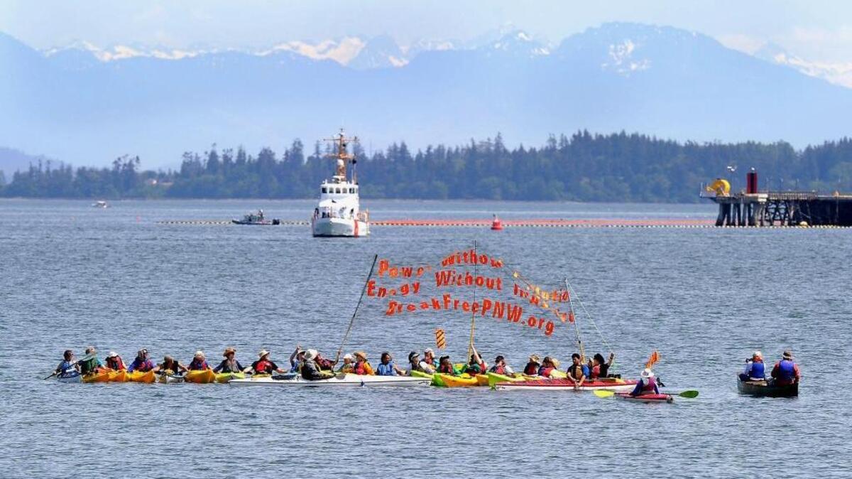 Break Free PNW kayaktivists unfurl their banner while out on the water in Fidalgo Bay east of Seafarer's Memorial Park in Anacortes, Friday, May 13, 2016. Hundreds of people in kayaks and on foot are gathering at the site of two oil refineries in Washington state to call for action on climate change and a fair transition away from fossil fuels.