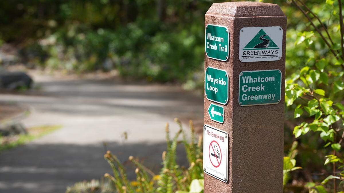 A signpost identifies the Whatcom Creek Greenway, a trail that runs along Whatcom Creek in downtown, Bellingham, Wash.