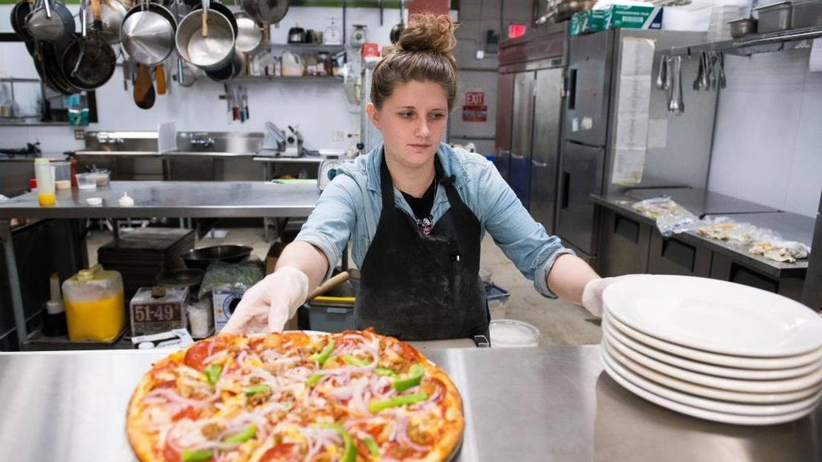 Katie Holland sets a "Robert DeNiro" pizza in the pass-through window at the new Greene's Corner location on James Street on Wednesday, Dec. 21, 2016, in Bellingham.