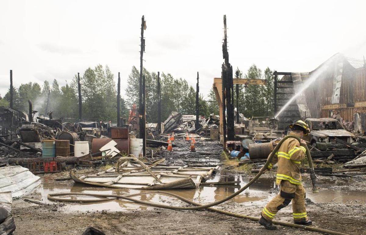 Firefighters from Whatcom County Fire District 7 work to put out remaining hotspots during a fire at Friberg Construction on Saturday, June 17, 2017, in Ferndale.