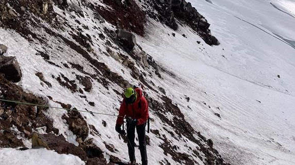 A Mountain Rescue volunteer rappels onto the Easton Glacier while searching for an overdue climber. A rescue helicopter flies overhead.
