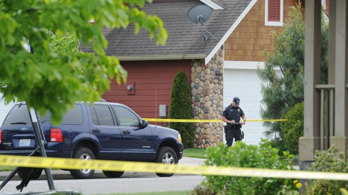 A Ferndale police officer stands in front of a house where a woman’s throat was slashed Friday, May 2, 2014, in the 5300 block of Patriot Place in Ferndale.