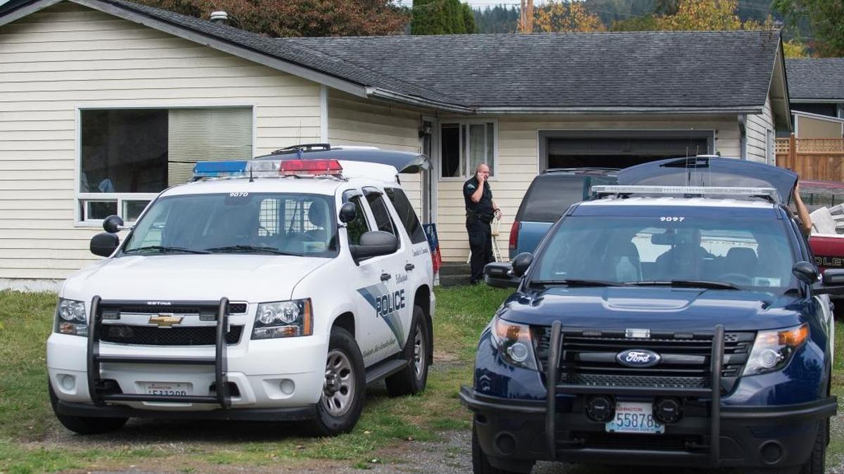 An officer from Bellingham Police Department talks on his phone in front of a house where two bodies were found on Saturday, Sept. 24.