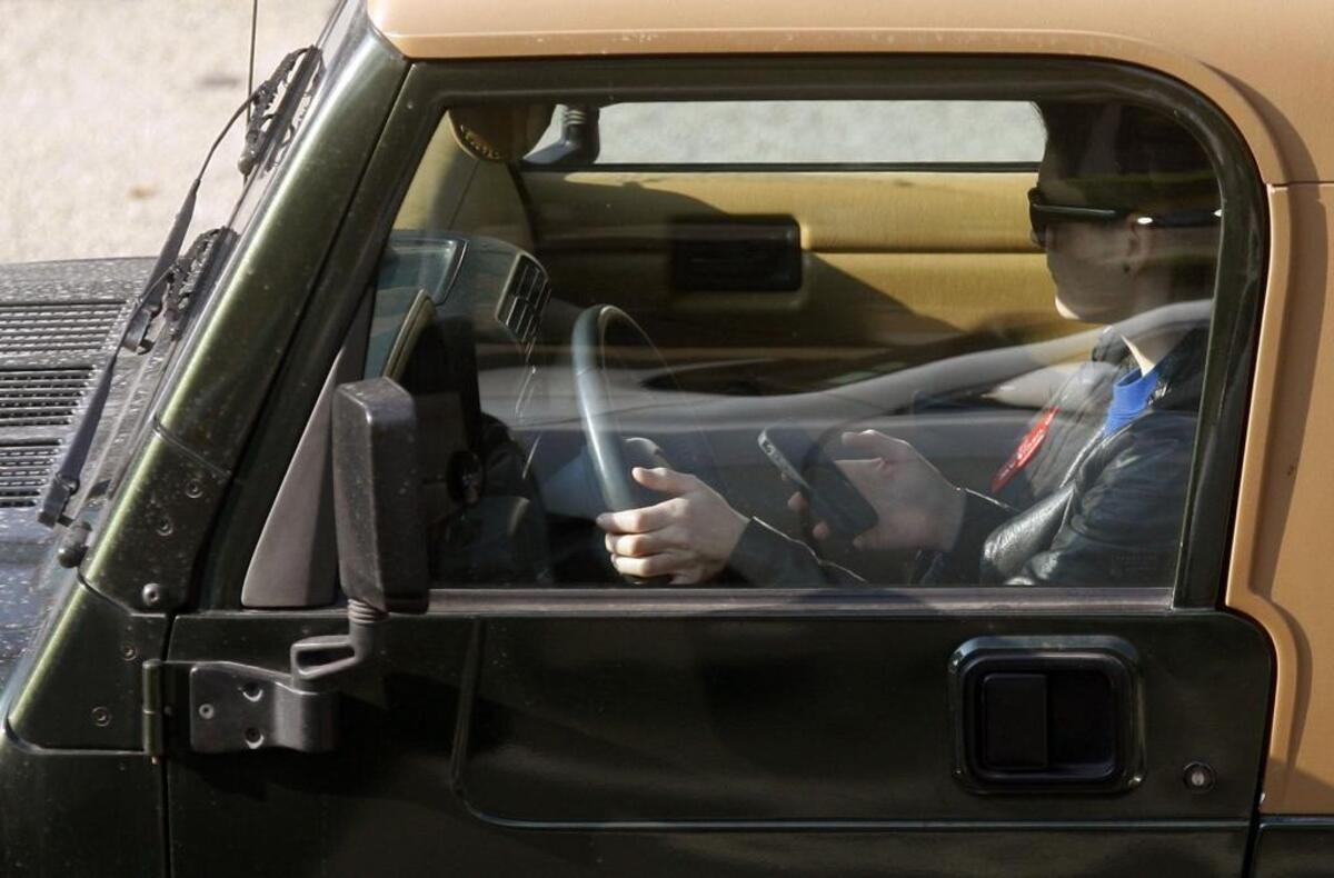 A driver uses an iPhone while driving in Los Angeles. A new Washington state law will take effect July 23, banning the use of cellphones while driving. The law extends to all electronic devices, will be enforced even when drivers are stopped at a traffic light or in traffic, and offenses will be reported to insurance providers.