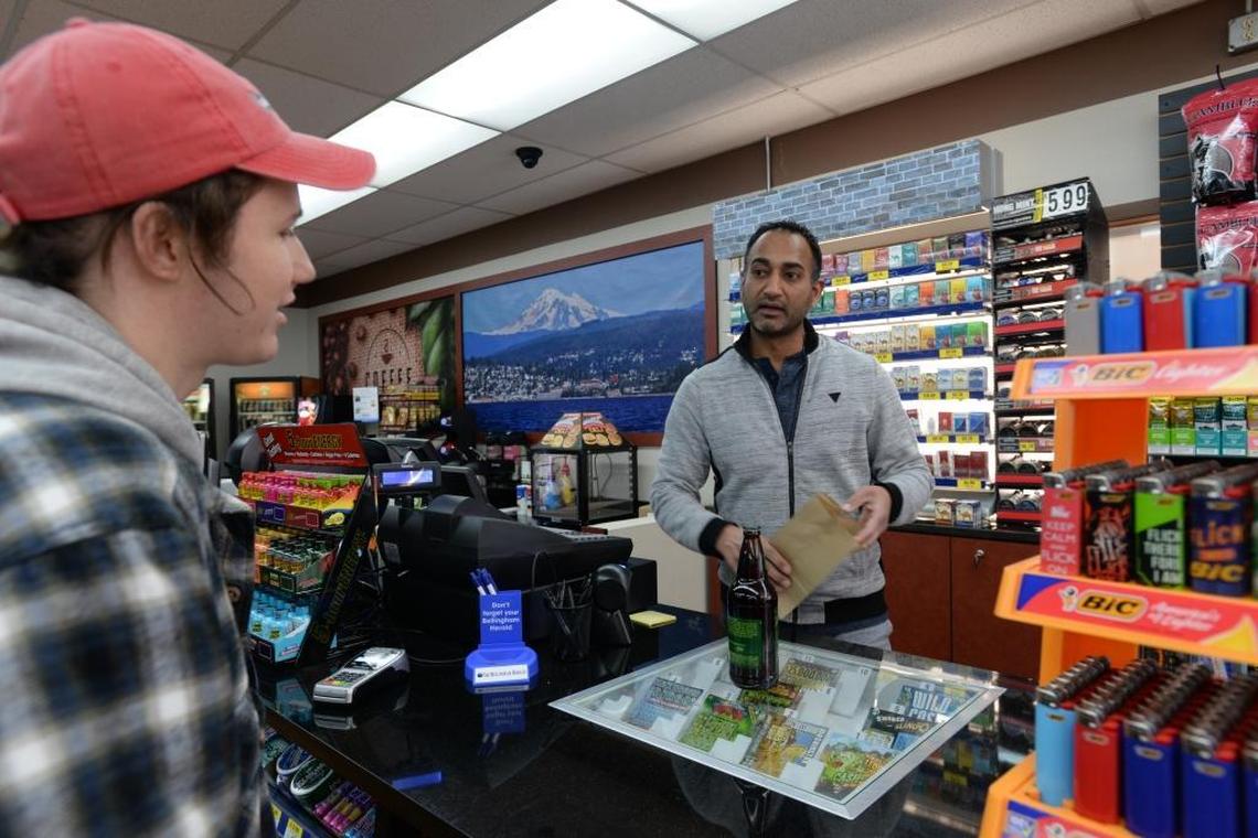 Charles Townsend buys a beer from owner Manny Sidhu at the new Elm St. Market in Bellingham, Monday, Feb.12, 2018.