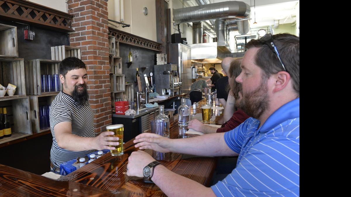 
Co-owner Jamison Rogayan serves a beer to Trevor Grove on the first day of business at Cosmos Bistro on the first floor of the Herald building on April 15, 2015. Getting financing to open the restaurant was much easier than a few years ago.
