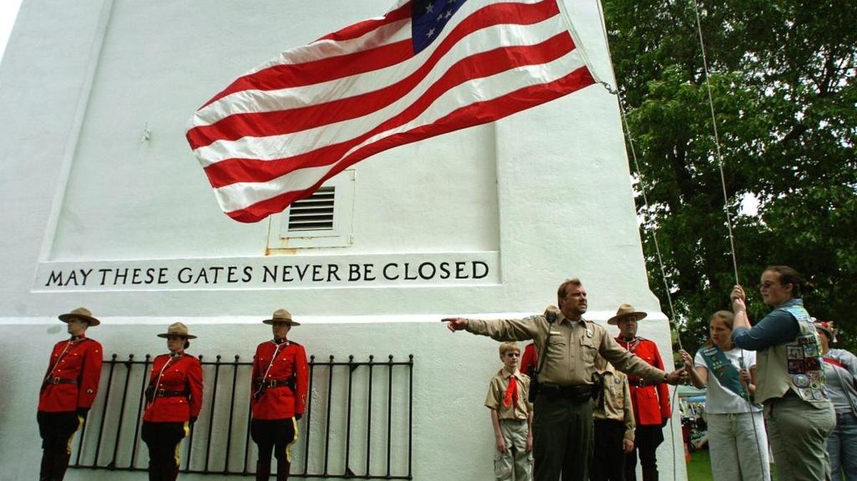 Park Ranger Brad McAdam directs Girl Scouts Keli Stewart, second from right, and Sierra Scott, far right, as they raise the U.S. flag in sync with a Canadian flag-raising during the Hands Across the Border celebration on June 10, 2007.