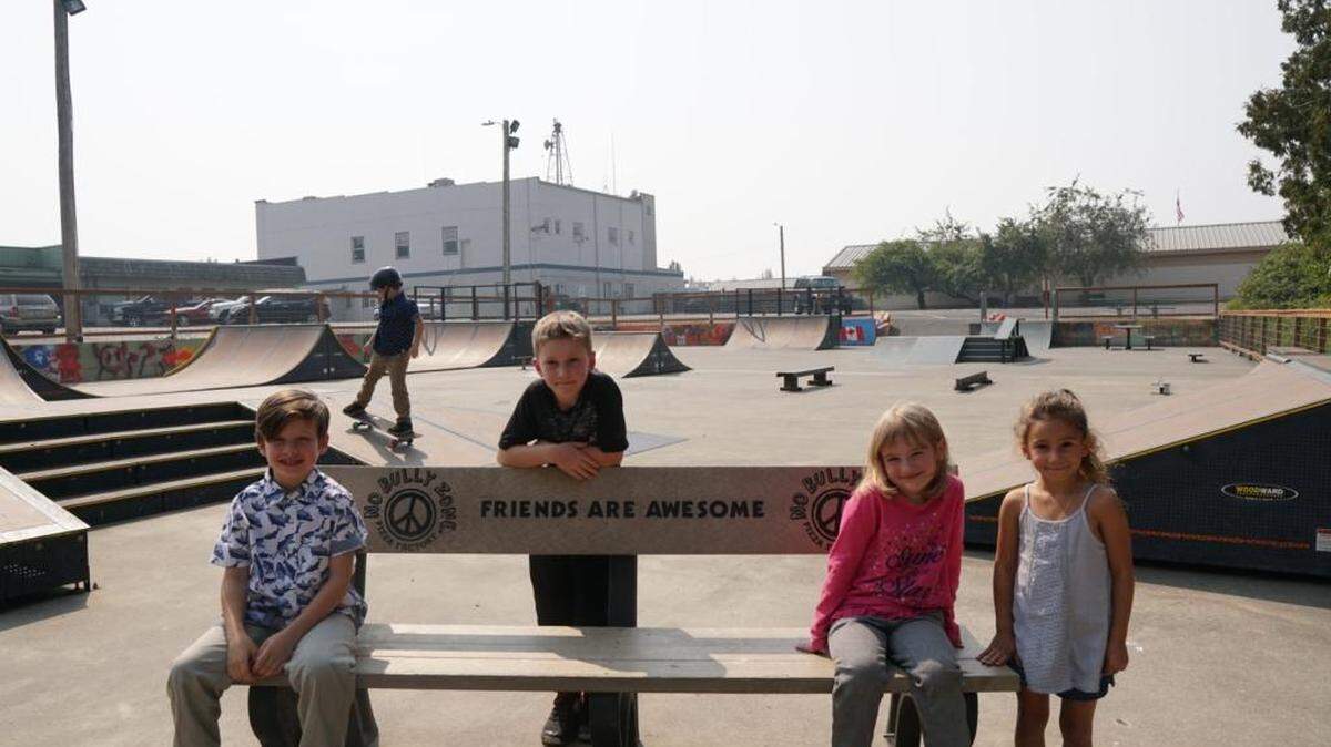 Jett Bowman 8, left, Grant Creydt 8, Hannah Creydt 5, Maddison Jones 5 hang out on the Buddy Bench while Knox Bowman, 8, skates at the Blaine skate park. If a student of any age feels he or she needs a friend – sometimes because of an incident of bullying – others can join that student on the Buddy Bench to meet and talk.