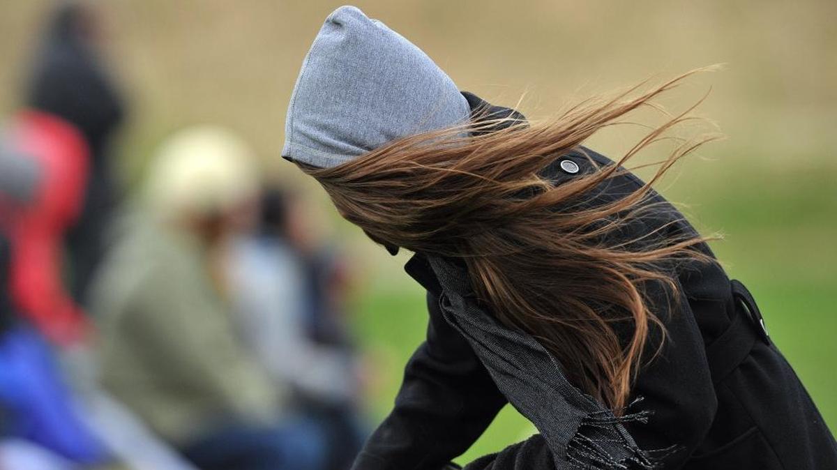 A woman’s hair gets in her face as high winds blowin Bellingham.
