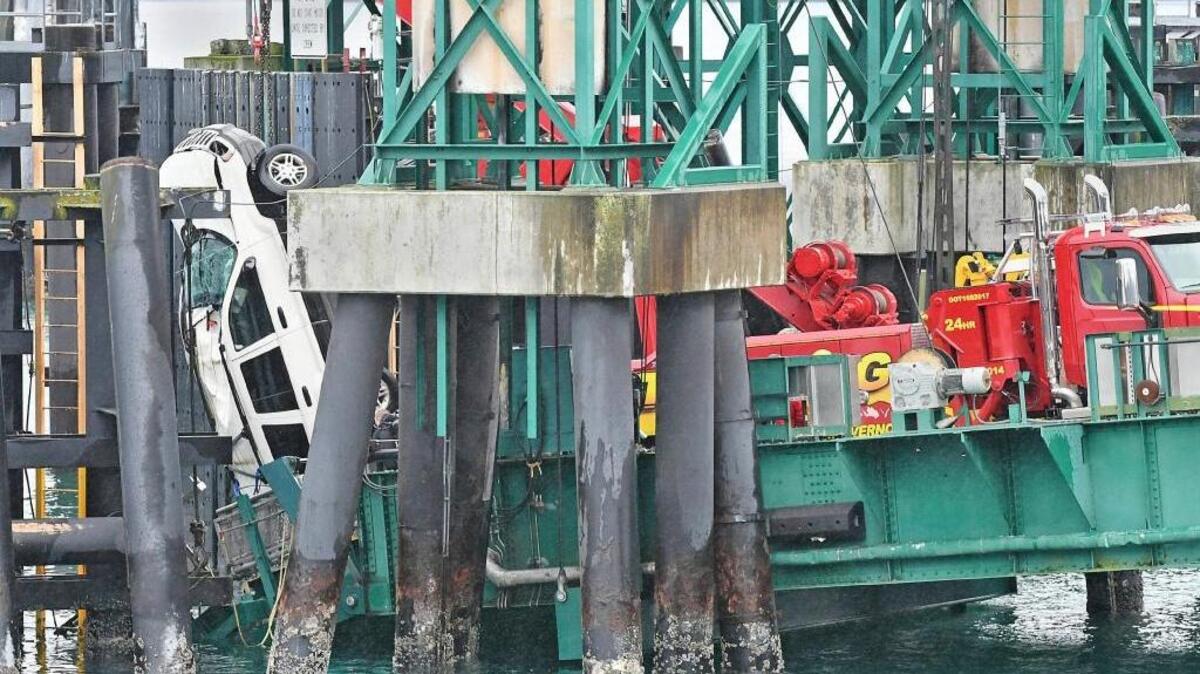 A tow truck lifts a white Jeep Cherokee vehicle out of the water at the Washington State Ferries terminal, Thursday, Jan. 25, 2018, in Anacortes, Wash. Authorities say a 30-year-old woman from Everett died after she drove her Jeep Cherokee through a barrier and off a dock at the Washington State Ferries terminal at Anacortes.