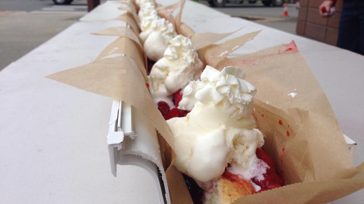 Strawberry shortcake with ice cream and whipped cream fills a 10-foot section of new gutter lined with waxed paper in front of the Lynden Chamber of Commerce office during a recent trial for the planned Farmers Day attempt at a world record 1,250-foot-long strawberry shortcake.
