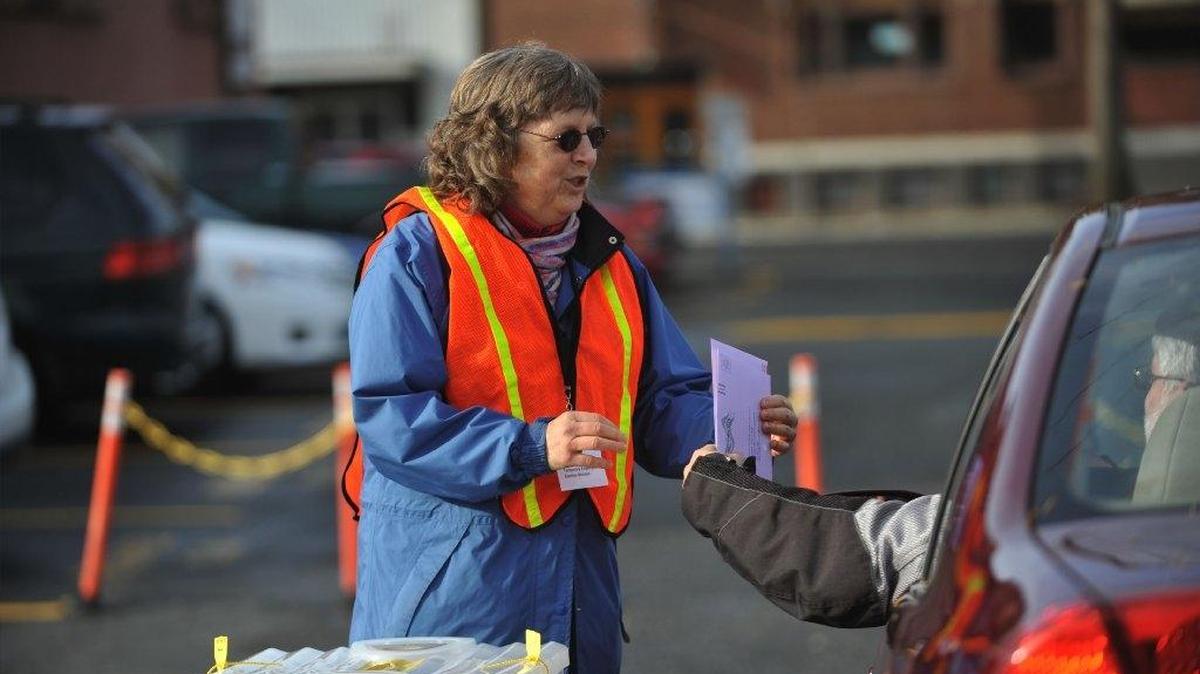 Volunteer election worker Carol Lord takes ballots from voters Nov. 5, 2012, at the drive-thru ballot drop-off at the Whatcom County Courthouse south parking lot in Bellingham. Voters used ballot boxes in record numbers in the Nov. 3, 2015, election.