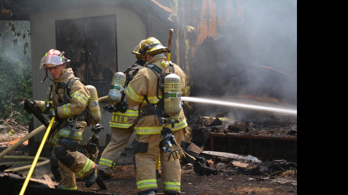 
Firefighters hose down the smoldering frame of a one-story house in the 7500 block of Woodland Road, east of Custer, that caught fire shortly before noon Friday, June 4.
