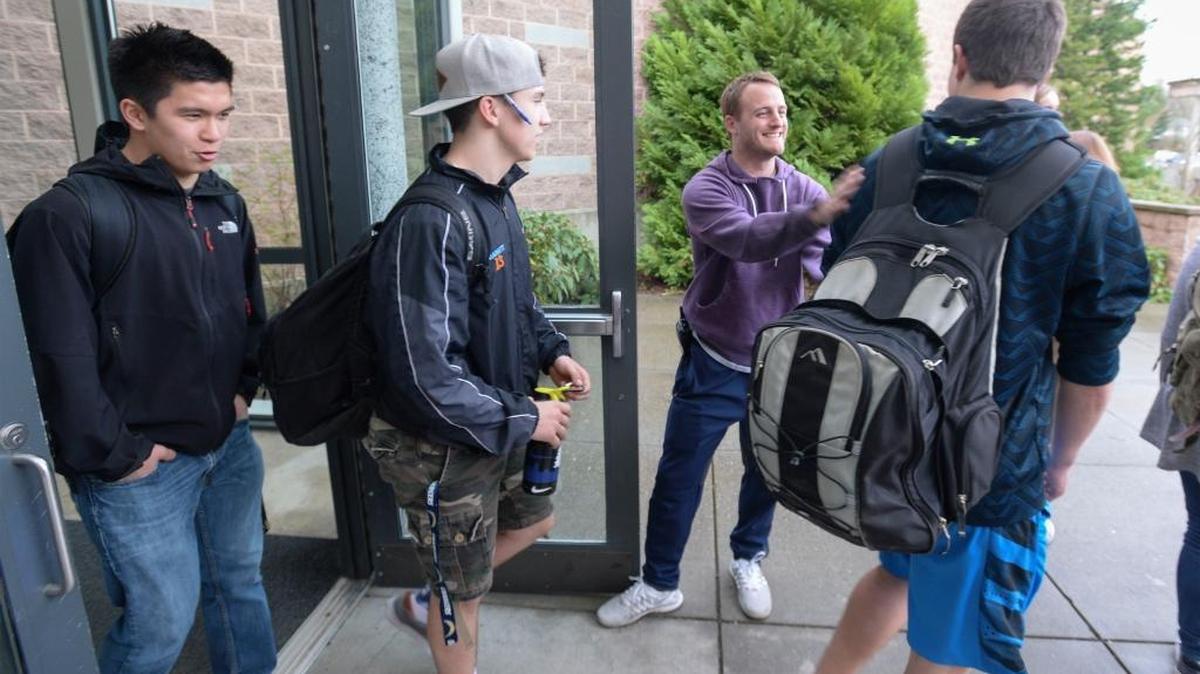 Squalicum High School campus security monitor Russ Robbinson, center, says goodbye to students Tyler Nguyen, left, Jase Barrett and Garrett Sorensen at the end of the school day, Wednesday, March 23, 2016. Starting in fall 2017, Bellingham high schools will start at 8:30 a.m. instead of 7:45 a.m.