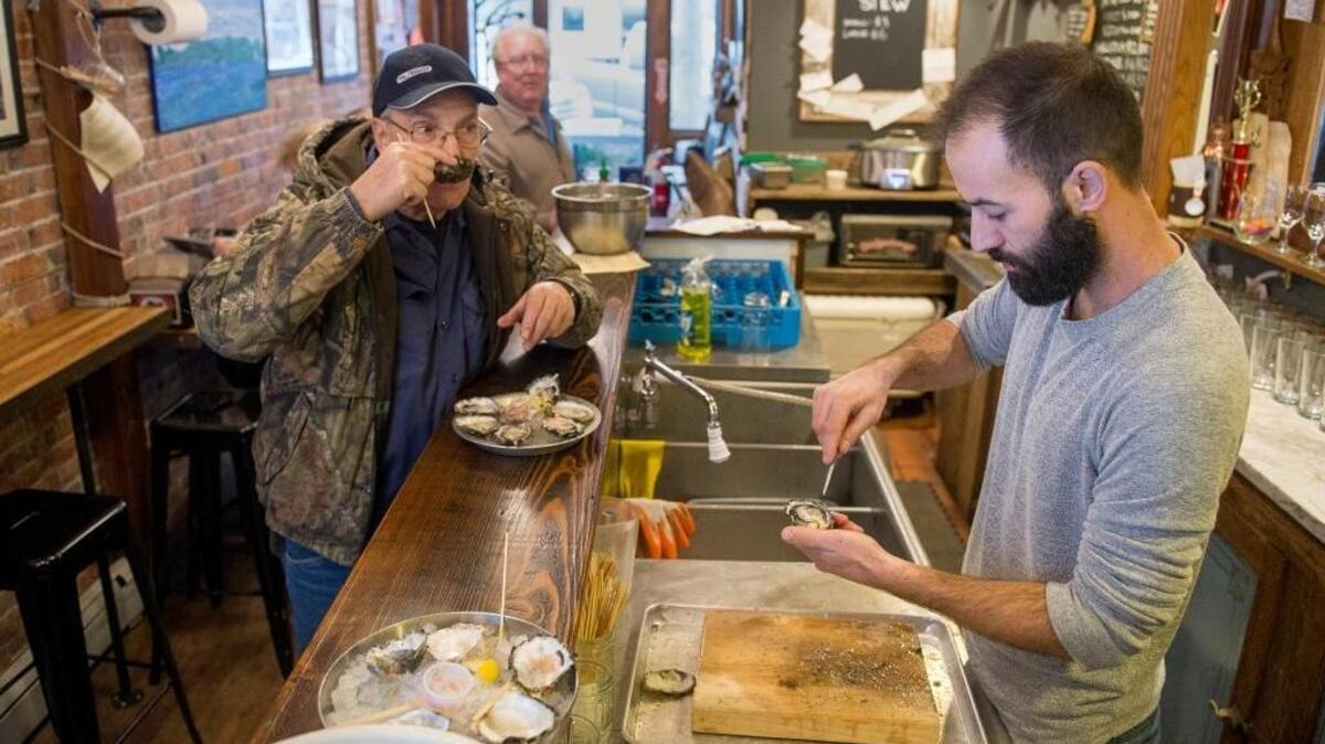 Drayton Harbor Oyster Co. co-owner Mark Seymour, right, shucks an oyster while customer and Blaine resident Marc Makowski eats an oyster on Friday, Dec. 2, at Drayton Harbor Oyster Co. in Blaine.