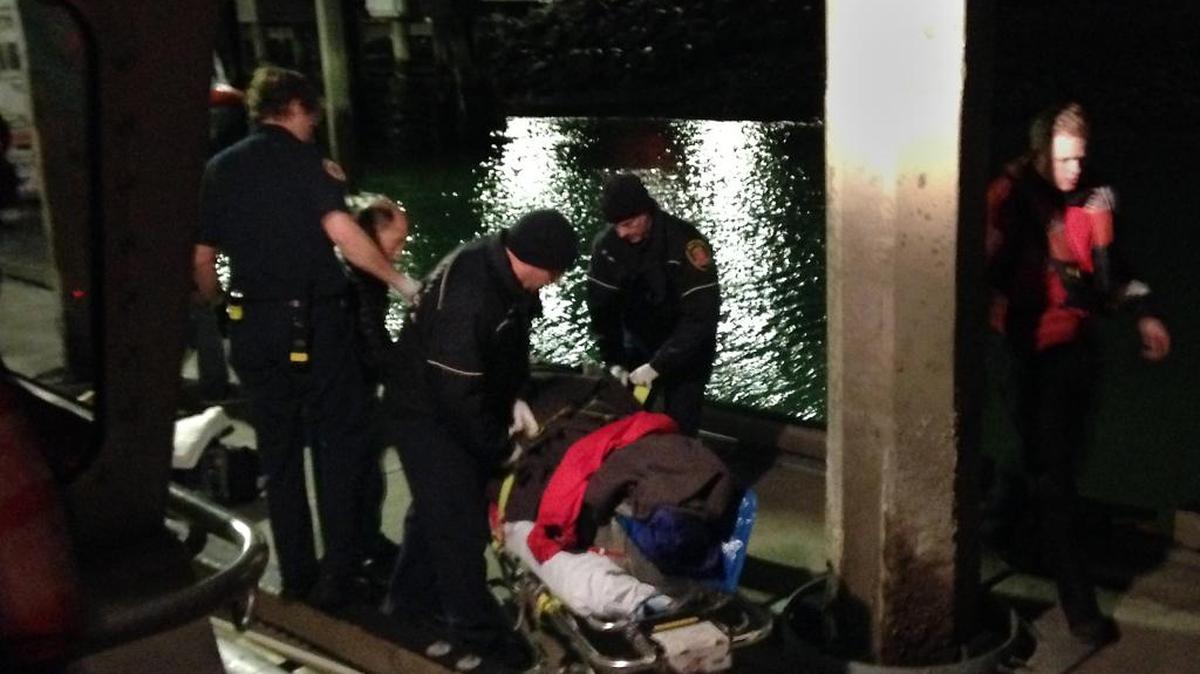 Bellingham firefighters and Coast Guard personnel move an injured man from a boat to an ambulance Saturday, March 5, after the man fell about 40 feet off the rocks by Wildcat Cove into the water.