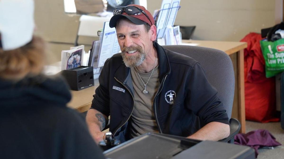 Robbie Adams, right, helps a homeless person while volunteering at the reception desk at the Lighthouse Mission Ministries’ Drop-In Center in Bellingham on May 31, 2017. Adams was homeless, but was in a program at the mission that provides housing and helps people become self-sufficient.