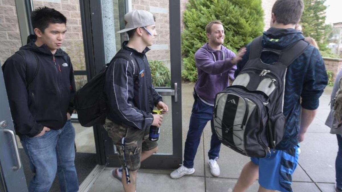 Squalicum High School campus security monitor Russ Robbinson, center, says goodbye to students Tyler Nguyen, left, Jase Barrett and Garrett Sorensen at the end of the school day on March 23, 2016. Starting in fall 2017, Bellingham high schools will switch to a block schedule of four classes a day.