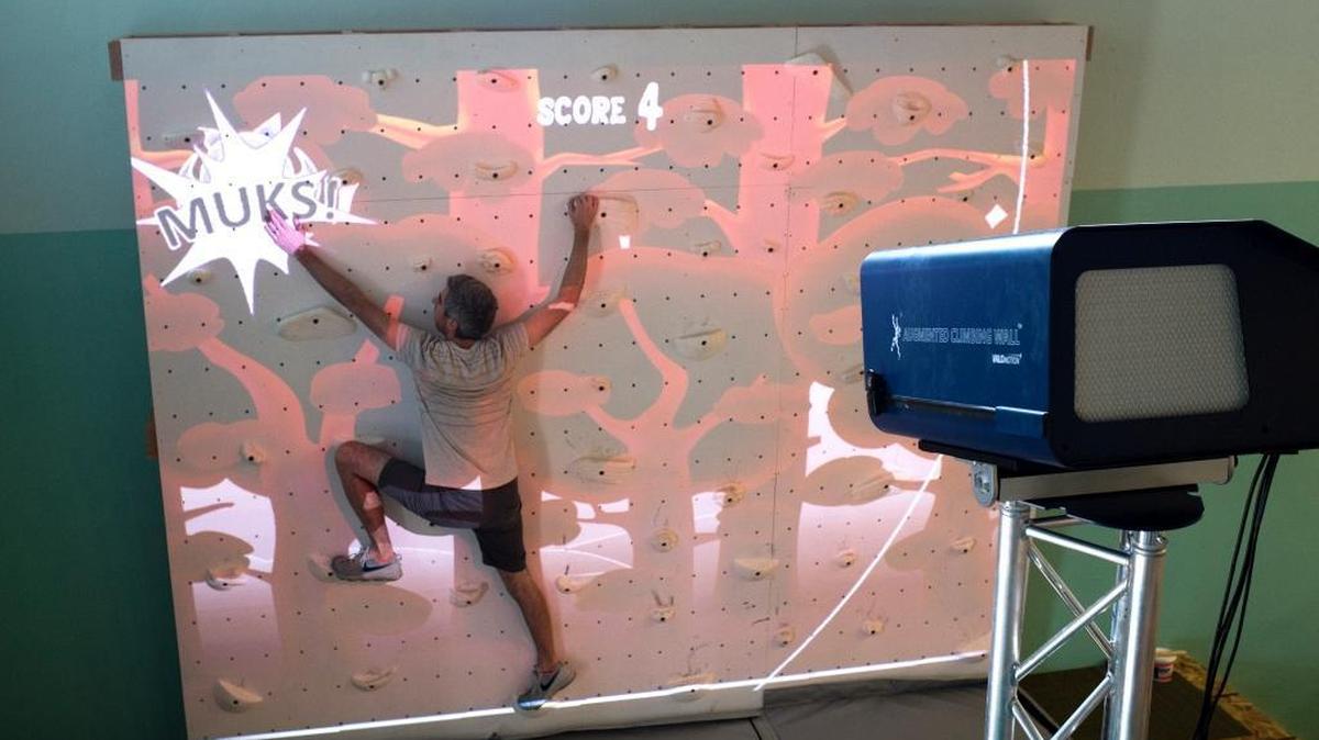 Kyle Fugier, business manager for Skookum Kids, demonstrates one of many games on an augmented climbing wall by Valo Motion at Perch and Play on Tuesday, Aug. 1, in Bellingham.