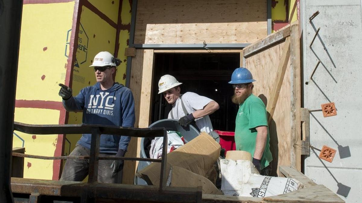 Tiger Construction employees, from left to right, Mike Hunholz, Kyle Brady and Malikai Knight remove trash and debris from the construction site of Options High School on Friday, Feb. 17, in Bellingham. Whatcom County experienced an increase in construction jobs in January, according to the latest numbers from the Employment Security Department.
