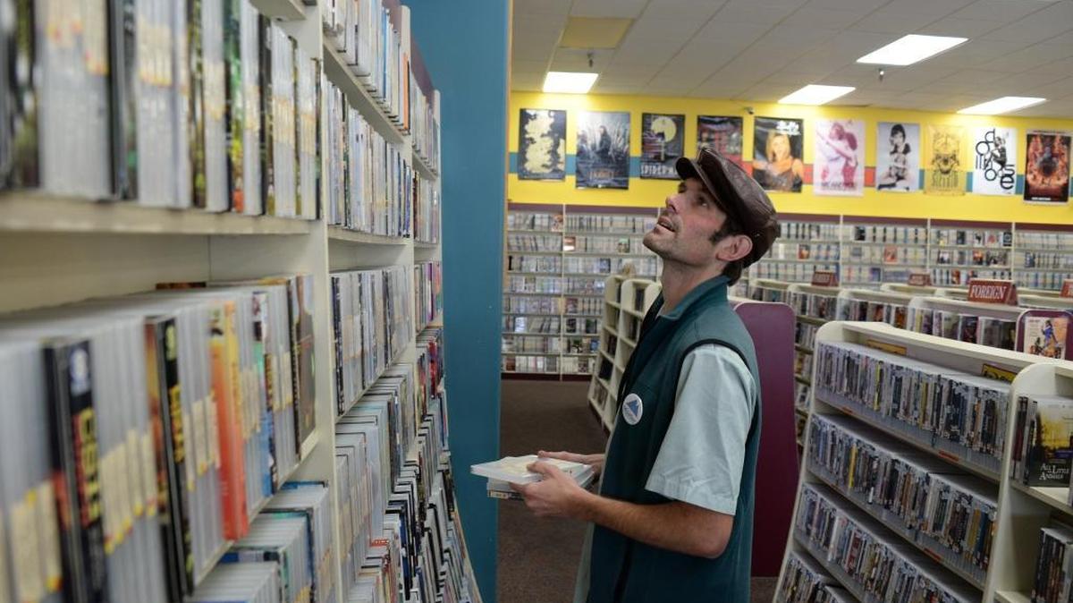 Chris Hazenberg stocks DVDs at Crazy Mike's Video in Bellingham on Friday, Oct. 14, 2016. The store is celebrating 20 years in business