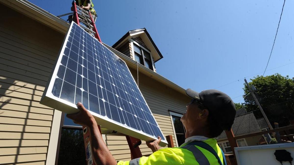 David Logan, top, and Tony Ringering from Western Solar install 24 solar panels on the roof of a house on Williams Street in Bellingham on July 25, 2013. Western Solar is one of three local solar businesses partnering with Sustainable Connections for a new program to encourage solar energy and benefit the Bellingham Food Bank.