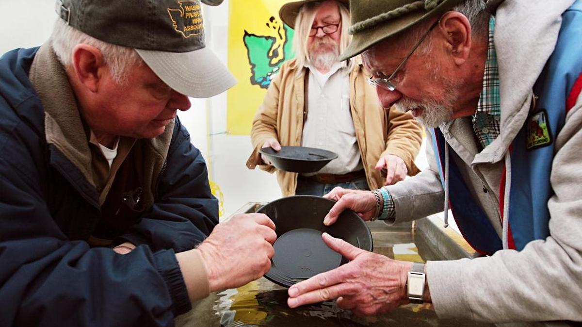 Peter Schott, right, tries gold panning at the Washington Prospectors Mining Association’s booth as Robert Cunningham, center, and Bob Deurbrock watch at the Mount Baker Rock and Gem Club’s show in 2011.