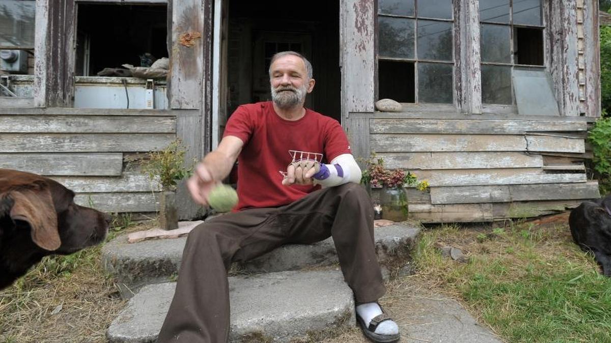 Jerry Bajema throws a ball for his dog Rue, left, and Tiny, outside his fire-damaged house Aug. 8, 2012, in Van Zandt. An accident with a chain saw left his left arm severely damaged and he’s unable to open his hand after gripping anything.