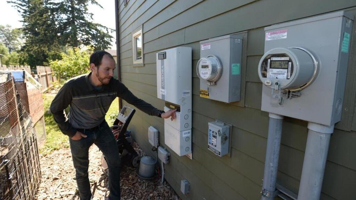 Jeff Aslan checks the solar power inverter on the side of his Net-Zero Energy house Wednesday, July 6, in Bellingham. Solar electric panels on the roof provide all the home’s power needs.