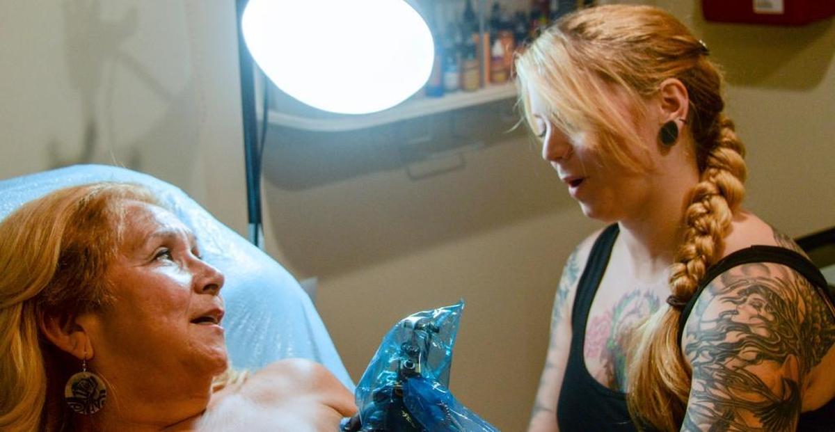 Breast cancer survivor Raynell Zuni talks with tattoo artist Shelly James at Chameleon Ink in Bellingham, Wash., on Friday, July 1, 2016, during her final session for a tattoo to cover her mastectomy scars.