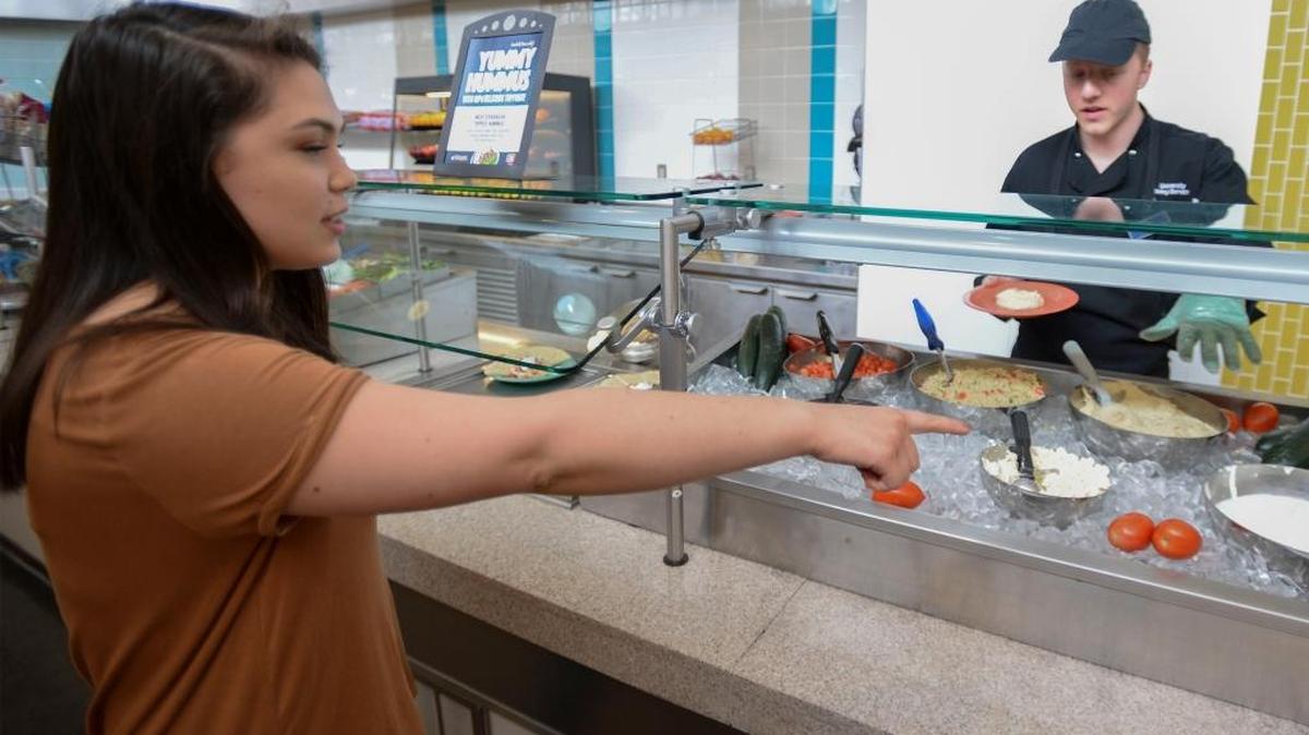 Student Joana Zhu, left, gets the hummus plate from student employee Sean Hutcheson at the Ridgeway Commons dining hall at Western Washington University in Bellingham Friday, April 15, 2016. The university is spending more on healthy, local and organic food.