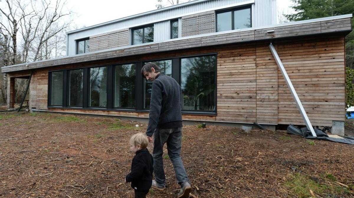Dan Welch and his son, Ezra Welch, 2, walk in front of their new energy-efficient house in Bellingham on Thursday Feb. 11, 2016. The house recently won the “Best Building Science” award from Green Builder Media.